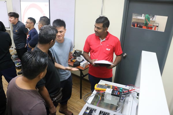 image showing an SLS Associate Engineer interacting with participants during a practical session on electrical basics