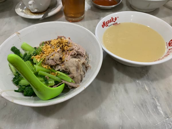 Image shows a bowl of Indonesian duck noodles and a bowl of homemade soup