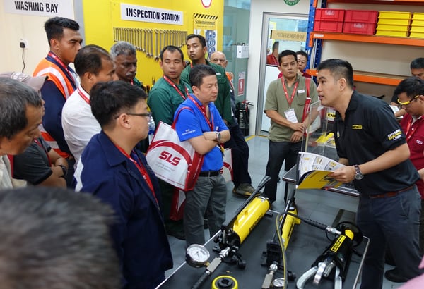 Image shows an Enerpac engineer conducting a live demo of hydraulic tools to a group of customers