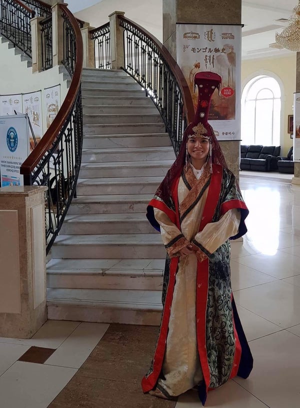 Image shows a woman dressed in traditional Mongolian deel and a headpiece