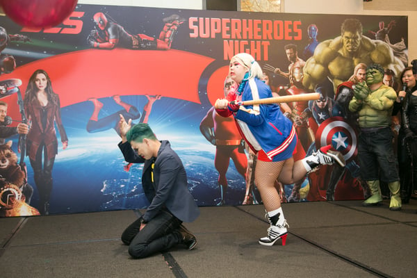 Image shows a man and a woman dressed as Joker and Harley Quinn on stage