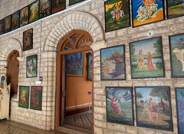 Image shows an array of paintings on a wall