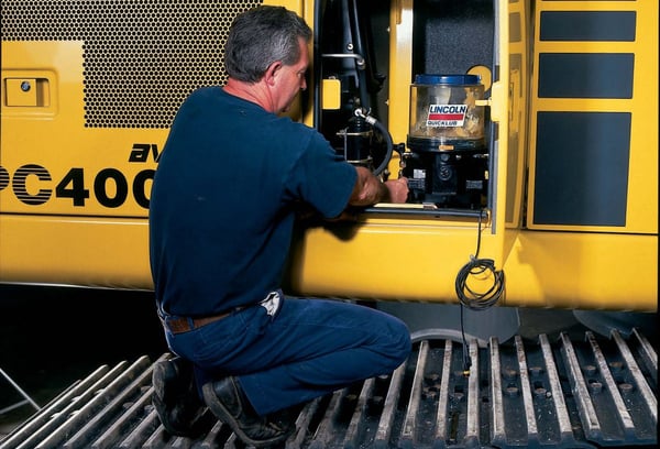 Image shows a man crouching in front of a lubrication system