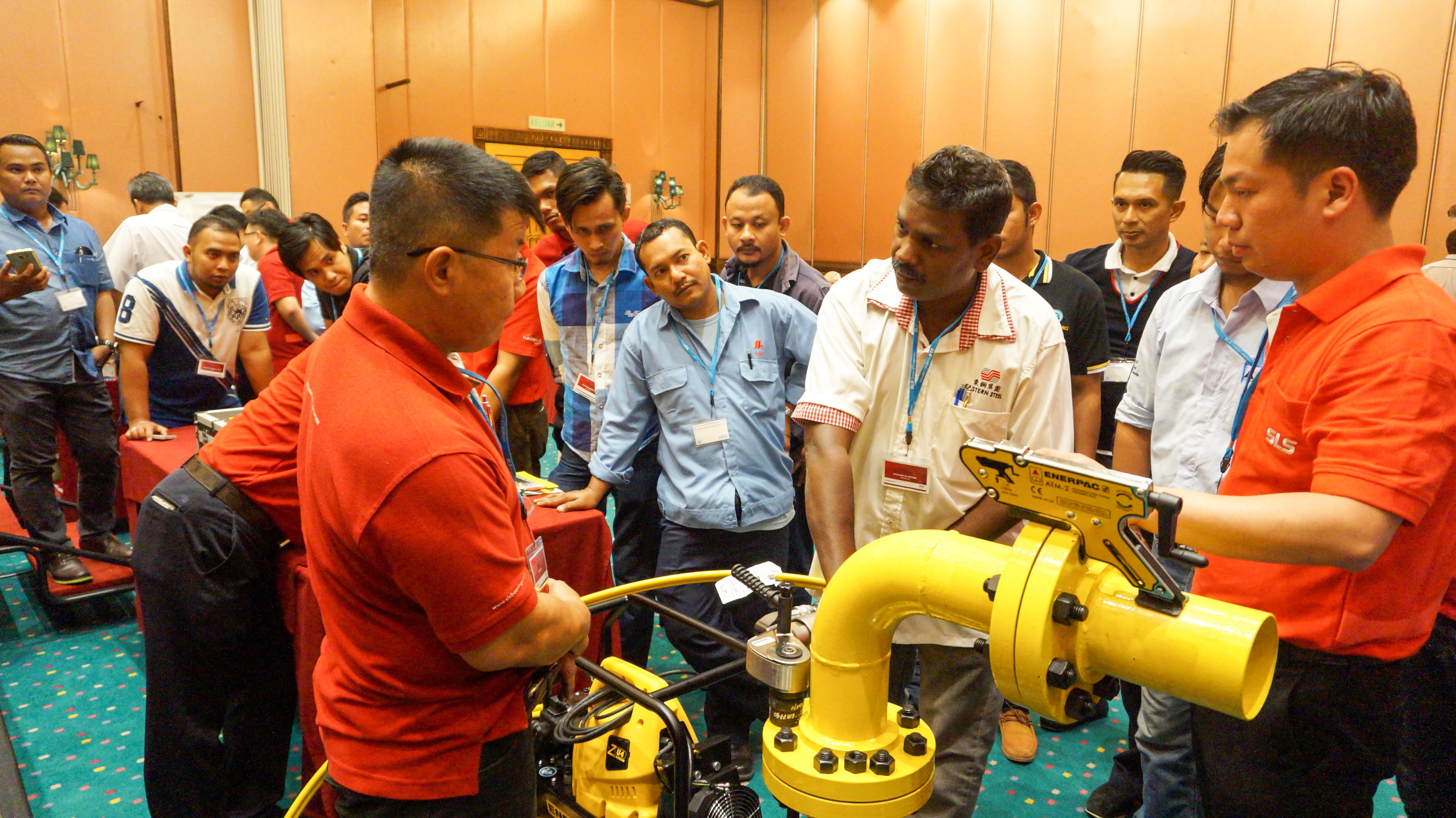 Image shows an SLS engineer explaining hydraulic equipment to a group of customers