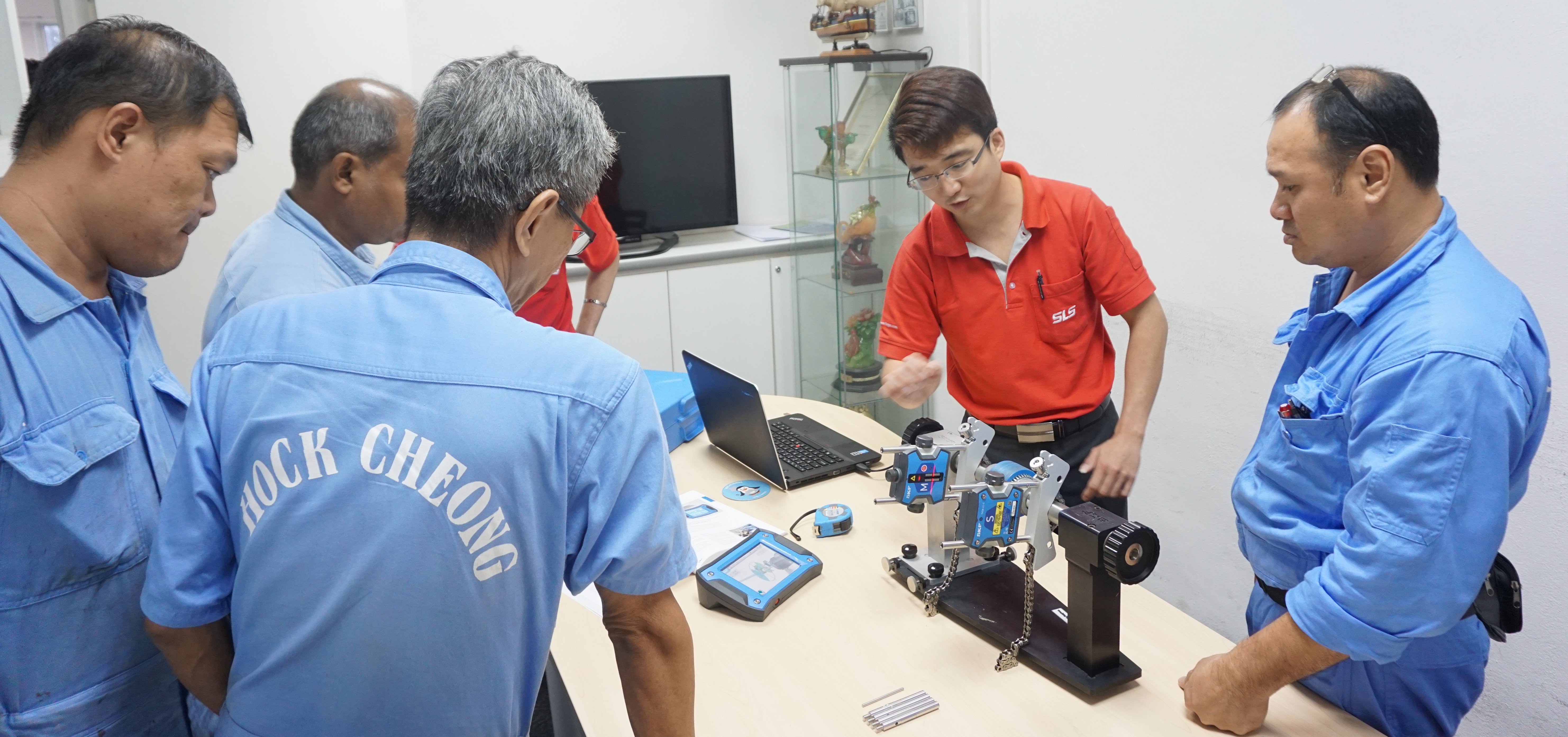 Image shows an SLS engineer explaining shaft alignment to employees of Hock Cheong Pte Ltd 